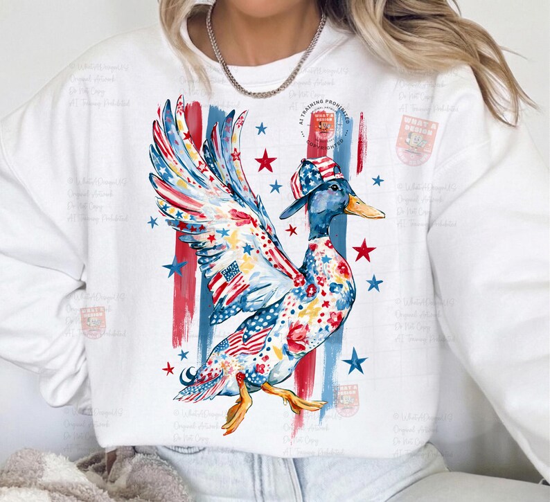 May include: A white sweatshirt with a colourful duck illustration. The duck is decorated with patriotic patterns, including the American flag, stars, and stripes. The design incorporates red, white, and blue colours, with the text "AT TRAINING PROHIBITED".