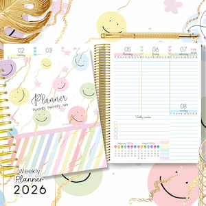 Puede incluir: Un planificador semanal 2026 con espiral dorada. La portada presenta un diseño de mármol con rayas pastel y caras sonrientes. El planificador abierto muestra un diseño semanal con páginas rayadas y un calendario.