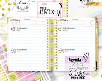 May include: An open spiral-bound planner with yellow wire binding, featuring lined pages for November 2025. The layout includes a calendar, daily headers in colorful text, and a gold pen. Text includes "MODELO: BMO23" and "Agenda 2 dias por pagina 2027".