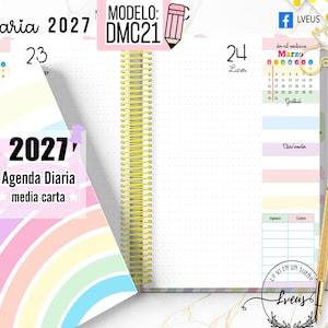 Puede incluir: Una agenda diaria 2027 con portada de arcoíris y encuadernación de espiral dorada. Las páginas interiores tienen cuadrícula de puntos, un calendario de marzo y secciones para gratitud y gastos. Un bolígrafo dorado se sitúa junto a la agenda.
