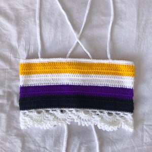 Peut inclure: Un haut crocheté à bretelles avec une bordure en dentelle blanche. Le haut est rayé de jaune, blanc, violet, noir et blanc.