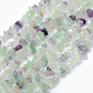Puede incluir: Una hebra de cuentas de fluorita chip de color verde, morado y blanco. Las cuentas son de forma irregular y tienen un acabado natural y pulido.