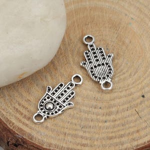 Può includere: Due ciondoli in argento a forma di mano di hamsa, un simbolo di protezione e buona fortuna. I ciondoli hanno disegni intricati e sono perfetti per la creazione di gioielli.