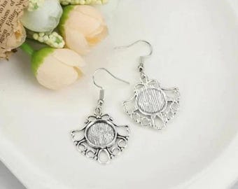 Puede incluir: Un par de pendientes de plata con un diseño delicado y ornamentado. Cada pendiente tiene un espacio redondo abierto para un camafeo u otro adorno.