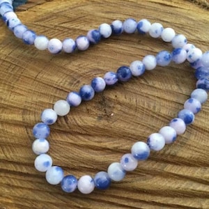 Peut inclure: Un brin de perles d'agate bleu et blanc. Les perles sont rondes et ont un aspect marbré.