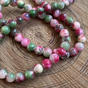 Peut inclure: Un collier de perles de jade rose et vert. Les perles sont rondes et ont un aspect marbré.