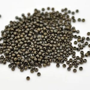 Pode incluir: Um grande monte de pequenas contas redondas de metal de cor bronze escuro.