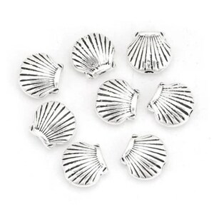 Peut inclure: Un ensemble de dix breloques en forme de coquillages en métal argenté. Les breloques sont en forme de coquillages avec une surface texturée détaillée.