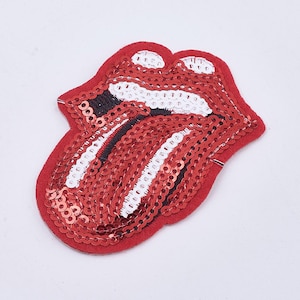 Peut inclure: Patch thermocollant rouge, blanc et noir en sequins représentant une langue qui sort. La langue est bordée de noir et a une bande blanche au milieu.