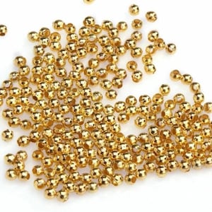 Peut inclure: Un grand nombre de petites perles rondes en métal de couleur dorée. Les perles ont un trou au centre pour être enfilées.