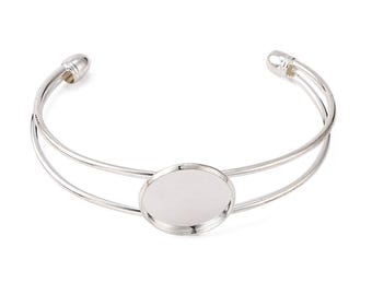 Puede incluir: Pulsera de plata con un cabujón redondo de vidrio transparente en el centro. La pulsera es de doble capa y tiene un diseño simple y elegante.