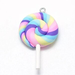 Könnte beinhalten: Ein bunter Wirbel-Lolli-Anhänger mit einem weißen Stiel. Der Lolli ist rosa, blau, gelb und lila. Der Anhänger hat eine silberne Öse zum Anbringen an einer Halskette oder einem Armband.