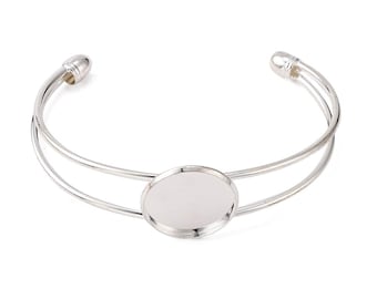 Puede incluir: Pulsera de brazalete de plata con un cabujón redondo de vidrio transparente en el centro. La pulsera es de doble capa y tiene un diseño simple y elegante.