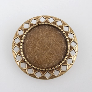 May include: A round, antique gold-toned metal pendant with a decorative, openwork design and a smooth, circular centre.