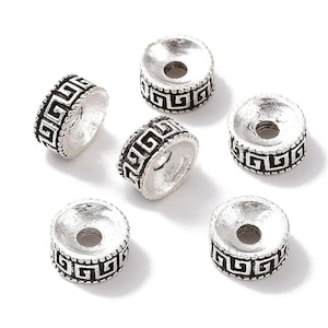 Può includere: Sei cappucci per perline in metallo color argento con un motivo a chiave greca nera. I cappucci per perline sono rotondi con un bordo rialzato.