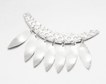 May include: A silver necklace with a crescent moon pendant and a fringe of silver leaves.