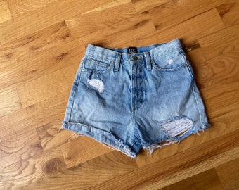 May include: Light blue denim shorts with distressed details and a frayed hem. The shorts have a button fly and five pockets. The brand name "Bdg" is visible on the waistband.