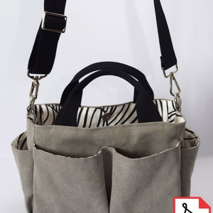 Op de afbeelding: Een grijze canvas draagtas met meerdere vakken en een verstelbare zwarte schouderband. De tas heeft een zwart-wit gestreepte voering. De tekst "A4 US LETTER PLOTTER" is in zwart op een witte achtergrond gedrukt. Een PDF-pictogram bevindt zich in de rechterbenedenhoek van de afbeelding.