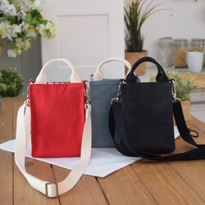 May include: Three small canvas tote bags with adjustable straps. The bags are red, blue, and black.