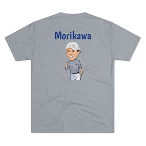 May include: A heather grey t-shirt with the name "Morikawa" printed in blue on the back. A cartoon image of a golfer wearing a white cap with the words "TaylorMade" on it is below the name.