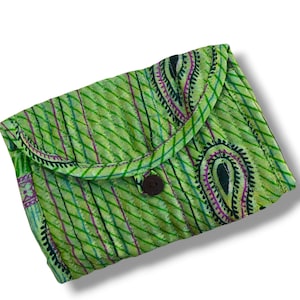 Pode incluir: Uma bolsa acolchoada verde-limão com um padrão paisley verde-escuro e roxo, apresentando linhas de costura diagonais. O acessório retangular possui uma aba arredondada fechada por um único botão circular castanho-escuro ao centro.
