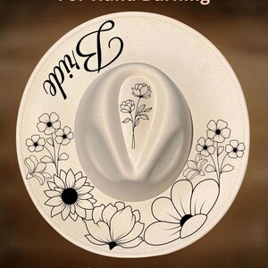 May include: A white fedora-style hat with the word "Bride" in black script. The hat features a floral design in black ink around the brim and a floral design on the crown. The text "For Hand Burning" and "CoolMoonDesigns" are also visible.