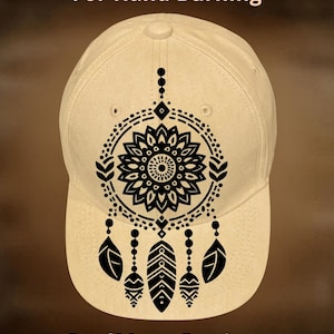 May include: A beige baseball cap with a black dreamcatcher design. The cap features the text "For Hand Burning" and "CoolMoonDesigns". The dreamcatcher design includes a central floral element, circles, and feather pendants.
