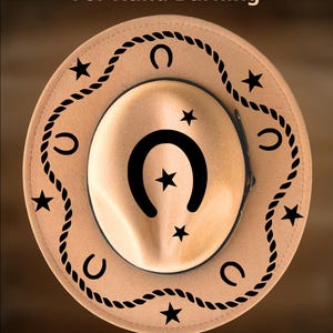 K&ouml;nnte beinhalten: Beigefarbener Cowboyhut mit schwarzen Seil-, Hufeisen- und Sternmustern. Der Text "For Hand Burning" und "CoolMoonDesigns" ist sichtbar. Der Hut hat ein schwarzes Band und ein zentrales Hufeisen- und Sternmuster.