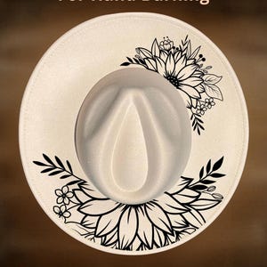 Puede incluir: Sombrero fedora color crema con un dise&ntilde;o floral negro en el ala. El texto "For Hand Burning" y "CoolMoonDesigns" est&aacute;n impresos en la imagen. El sombrero tiene una corona redondeada y un ala ancha.