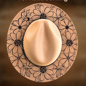 May include: A tan fedora hat featuring a black line art floral pattern around the brim. The text "For Hand Burning" is printed at the top and "CoolMoonDesigns" is printed at the bottom of the image in a light tan font color.