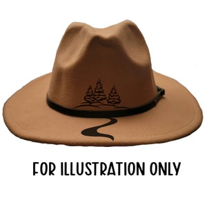 May include: A tan fedora hat with a black leather band and a black graphic of three pine trees and a winding road. The text "FOR ILLUSTRATION ONLY" is printed in black at the bottom of the image.