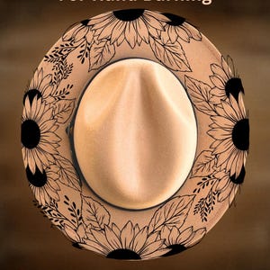 May include: A tan fedora hat featuring a black line art design of sunflowers and leaves burned into the brim. The text "For Hand Burning" appears at the top and "CoolMoonDesigns" is printed at the bottom in a simple, light-coloured font.