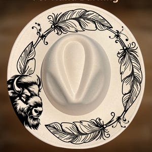 May include: A cream-coloured cowboy hat with a decorative black feather and bison design. The text "For Hand Burning" and "CoolMoonDesigns" are printed on the hat.