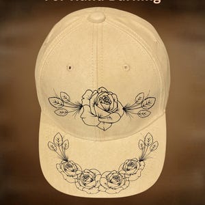 May include: A beige baseball cap with a floral design. The cap features a black rose and leaf design on the front and brim. The text "For Hand Burning" and "CoolMoonDesigns" are printed on the cap.