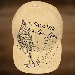 May include: A beige baseball cap with a black illustration of a quill, ink bottle, and scroll. The text "Write Me a Love Letter" is above the illustration. The words "For Hand Burning" and "CoolMoonDesigns" are also printed on the cap.