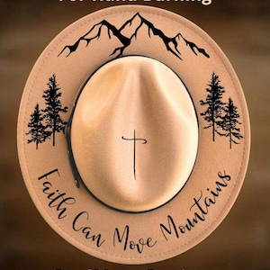 May include: Tan fedora-style hat with a black mountain range and pine tree design. The hat features the text "Faith Can Move Mountains" and a cross. The words "For Hand Burning" and "CoolMoonDesigns" are also visible.