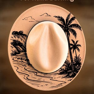 May include: A tan fedora hat with a cream-colored crown and a black brim. The hat features a black line drawing of a tropical scene, including palm trees and a shoreline. The text "For Hand Burning" and "CoolMoonDesigns" are displayed on the hat.