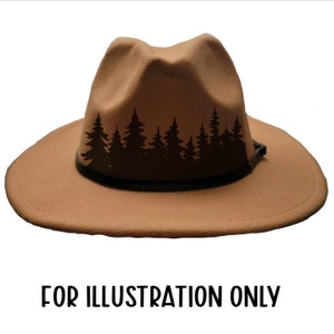 May include: A tan fedora-style hat with a black leather band and a forest silhouette design. The hat has a wide brim and a pinched crown. The text "FOR ILLUSTRATION ONLY" is at the bottom.