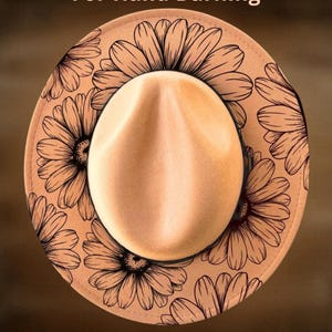 May include: A tan fedora hat with a light brown crown and a wide brim. The brim features a repeating pattern of large, stylized black flowers. The text "For Hand Burning" and "CoolMoonDesigns" are printed on the hat.