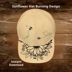 May include: A beige baseball cap with a black sunflower design on the brim. The cap features two black bees with dotted flight paths and a heart. The text "Sunflower Hat Burning Design" and "Instant Download" are visible.