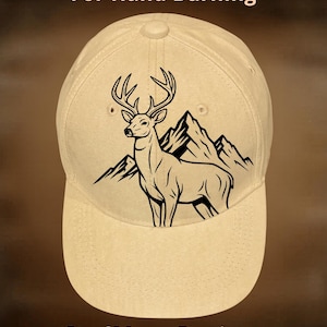 May include: A tan baseball cap featuring a black graphic of a deer standing in front of mountain peaks. The text "For Hand Burning" appears at the top, and "CoolMoonDesigns" is printed at the bottom of the image.