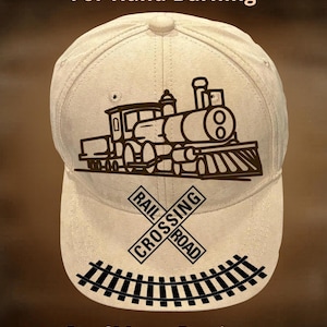 May include: A beige baseball cap with a train design. The cap features a black train illustration, a railroad crossing sign, and the text "For Hand Burning" and "CoolMoonDesigns".
