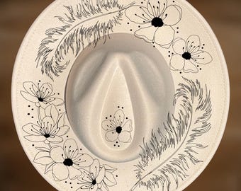 May include: A cream-colored fedora hat featuring black line art illustrations of two feathers and several flowers. The text "For Hand Burning" appears at the top, and "CoolMoonDesigns" is printed at the bottom of the image.