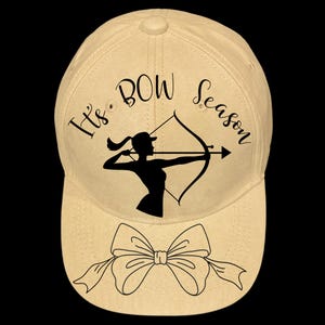 Könnte beinhalten: Eine beige Baseballkappe mit einer schwarzen Silhouette einer Frau mit Pfeil und Bogen. Der Text "It's Bow Season" ist um das Bild herum geschrieben. Eine schwarze Schleife befindet sich auf der Vorderseite der Kappe.