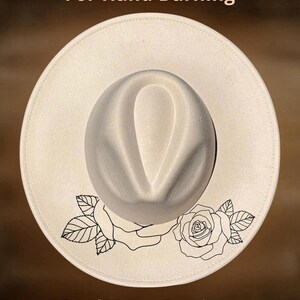 May include: Cream-colored fedora hat with a gray crown and a wide brim. The brim features a black floral design with roses and leaves. The text "For Hand Burning" and "CoolMoonDesigns" are printed on the hat.