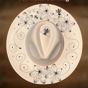 May include: Cream-coloured fedora hat with black floral and bee designs. The hat features the text "For Hand Burning" and "CoolMoonDesigns". The brim is decorated with stylized flowers and bees.