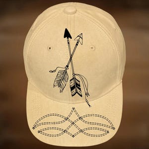 May include: A tan baseball cap with a black arrow design and the text "For Hand Burning" and "CoolMoonDesigns". The cap features a decorative stitched pattern on the brim.