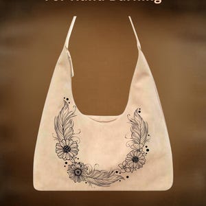 Op de afbeelding: Beige schoudertas met een bloemen- en veermotief. De tas heeft de tekst "For Hand Burning" en "CoolMoonDesigns". De tas heeft een gebogen bovenkant en een enkele riem.