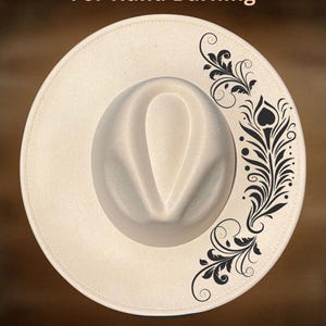 May include: A cream-coloured fedora hat featuring a black floral design on the brim. The hat has a classic teardrop crown and a wide brim. The text "For Hand Burning" and "CoolMoonDesigns" are visible.