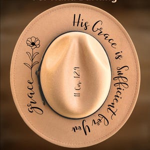 May include: A tan fedora hat with the text "His Grace is Sufficient for You" and "11 Cor. 12:9" in black script. The hat also features a floral design and the words "grace" and "CoolMoonDesigns".